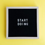Black message board with 'Start Doing' on a bright yellow background for inspiration.